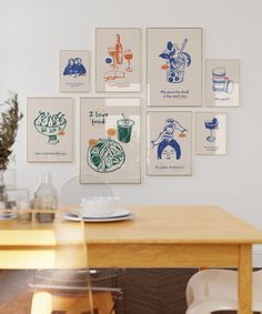 a wooden table topped with a white plate next to a wall covered in framed pictures