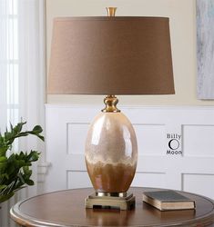 a table with a lamp on top of it and a book next to the lamp