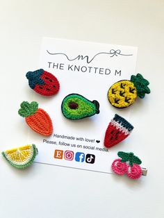 crocheted fruit and vegetable brooch pins are displayed on a white card board