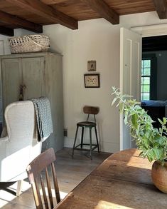 a wooden table and chairs in a room with white walls, wood beams and exposed ceiling