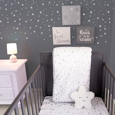 a baby's crib with stars on the wall and a white teddy bear