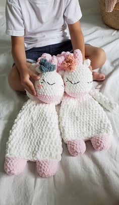 two crocheted stuffed animals sitting on top of a white bed next to each other