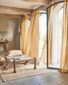 a living room filled with furniture and windows covered in yellow draping next to a wooden table