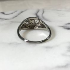 an antique diamond ring sits on a marble surface