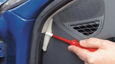 a person is opening the door of a blue car with a red tool in it