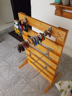 a wooden rack with clothes hanging from it's sides on a tile floor next to a wall