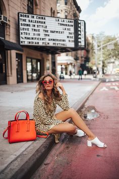 a woman is sitting on the curb with her handbag