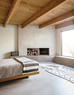 a bedroom with a large bed and a fireplace in the corner next to a window