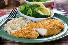 a green plate topped with chicken, rice and broccoli next to a glass of water