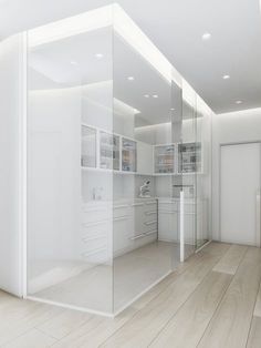 an empty white room with glass walls and shelves on the wall is shown in this image