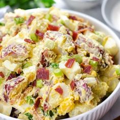 a white bowl filled with potato salad next to other bowls