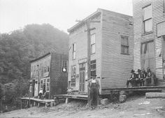 an old black and white photo of people standing on the back of a house that is being built