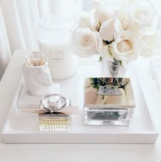 there is a white tray with flowers and other items on it