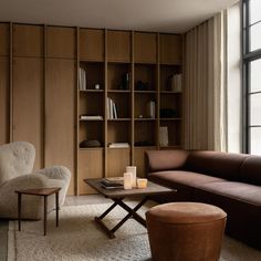 a living room with bookshelves and a couch next to a table in front of a window