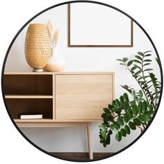 a wooden cabinet sitting next to a potted plant on top of a table in front of a mirror