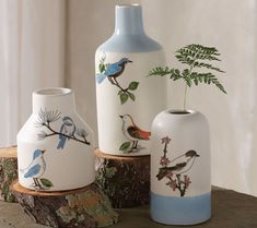 three vases sitting on top of a wooden table next to a potted plant