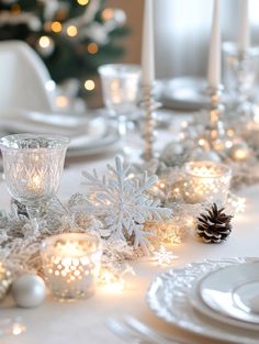 the table is set for christmas dinner with candles and snowflakes on it