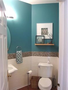 a bathroom with a toilet, sink and mirror in it's center wall color is teal