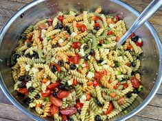 a bowl filled with pasta salad on top of a wooden table