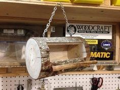 a wooden bird feeder hanging from a chain in a store filled with woodworking supplies