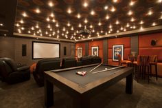 a game room with a pool table, couches and chairs in front of a projector screen