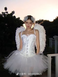 a woman in a white corset with angel wings on her head and dress