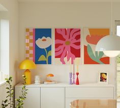 a living room with paintings on the wall and a table in front of some plants