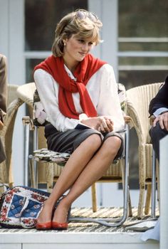 a woman sitting in a chair wearing a red scarf