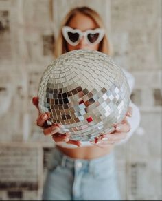 a woman wearing sunglasses holding a disco ball