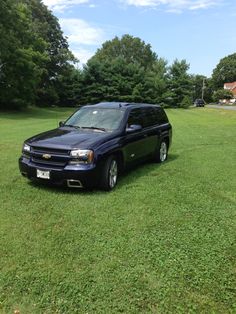 a black suv is parked in the grass