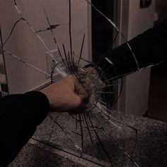 a hand holding a broken glass in the middle of a counter top with another hand reaching for it