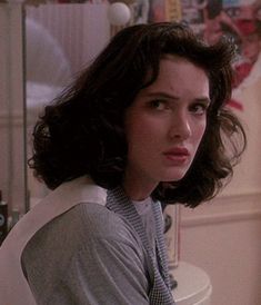 a woman sitting in front of a cake on top of a white table next to a wall