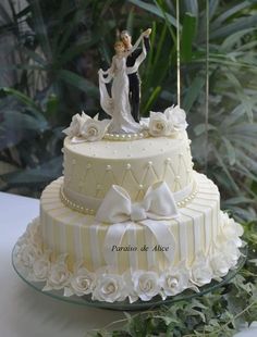 a wedding cake decorated with white flowers and a bride and groom figurine on top