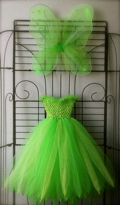 a green dress hanging up on a rack next to a butterfly wall decoration in a room