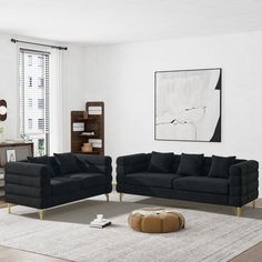 a living room with two black couches and a white rug on the floor in front of a window