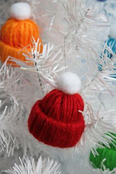 three knitted hats hanging from a white christmas tree