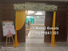 an entrance to a banquet hall decorated with yellow drapes and white flowers on it