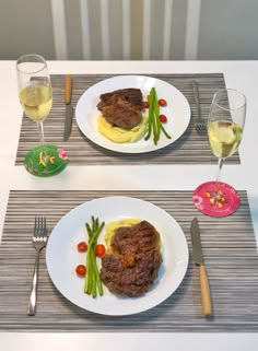 two white plates topped with meat and veggies