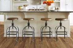 three stools in front of a kitchen island with flowers on the counter and shelves