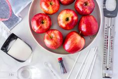 apples in a bowl next to measuring tape and utensils on a white table