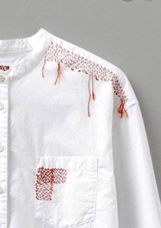 a white shirt with red embroidery on the chest