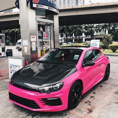 a pink car parked in front of a gas station