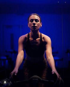 a woman riding a bike in a dark room