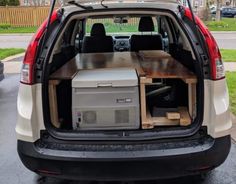 the back end of a small van with an open hatchback and table in it