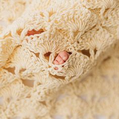 a baby's feet are poking out of a crocheted blanket that has been folded over