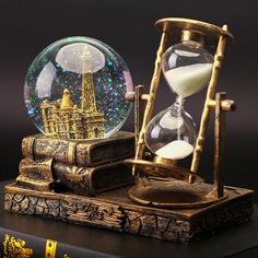 an hourglass sitting on top of a book next to a glass globe with the eiffel tower in it