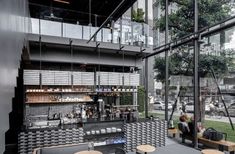 the inside of a building with tables and benches in front of large windows that are filled with people