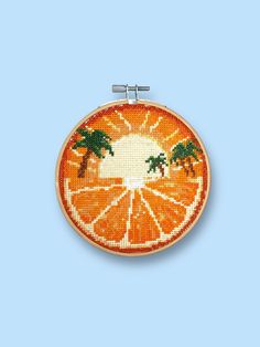 an orange slice with two palm trees on it is featured in this cross stitch pattern