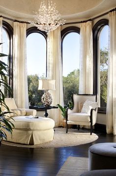 a living room filled with lots of windows and furniture in front of large arched windows