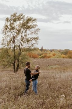 a man and woman standing in the middle of a field